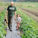 Farmer Chris Bodnar walks a row of vegetables on his farm with his daughter