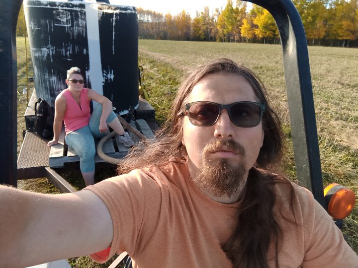 Anton Goulko and Dorothy Penner of Ural Farms on a tractor in the field.