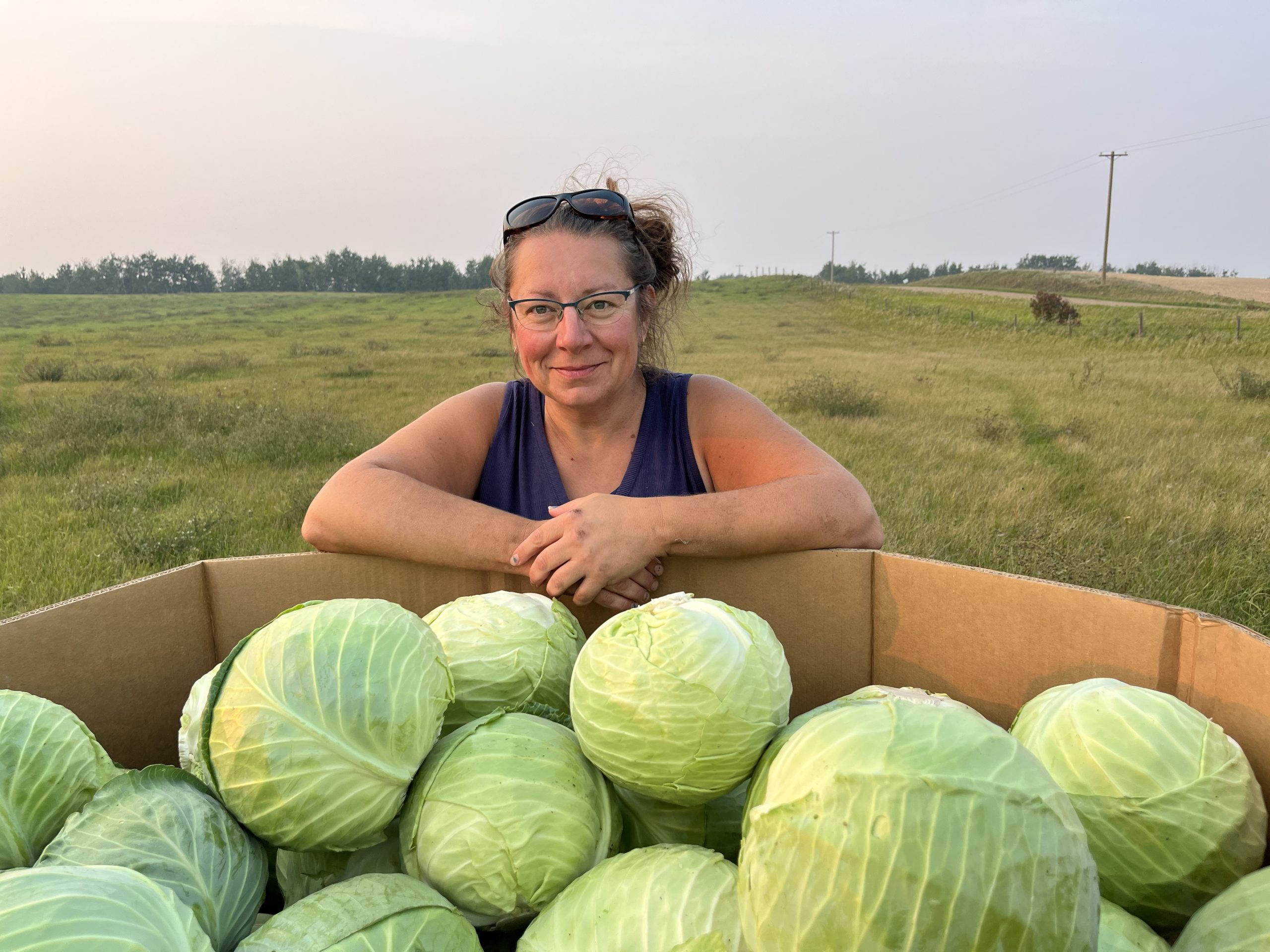 Kim Ross standing beside a bulk bin of green cabbages